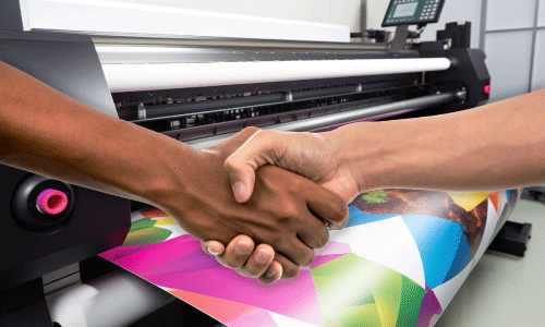 two people shaking hands over a digital printer